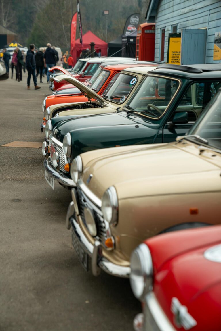 Lineup of colorful vintage Mini cars at an outdoor car meet in England, showcasing classic automotive design.